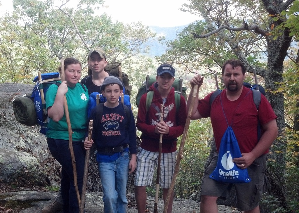 Family wearing DIY wooden backpack frames on a hiking trip