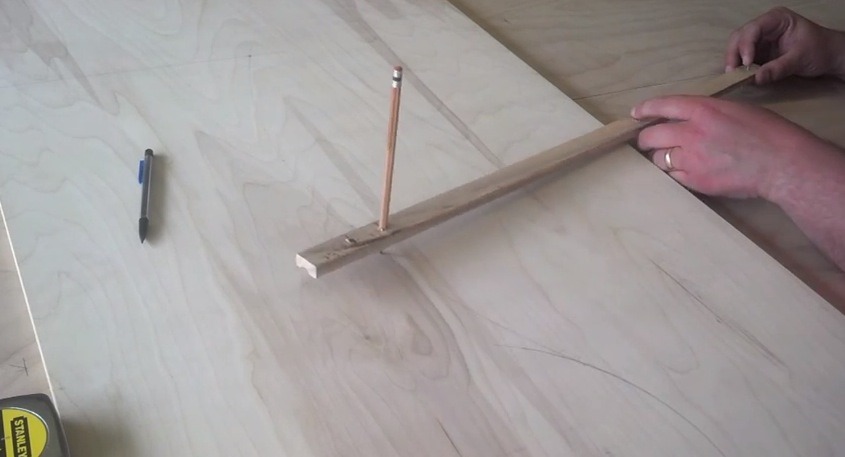 Makeshift beam compass used to mark the plywood desk arcs